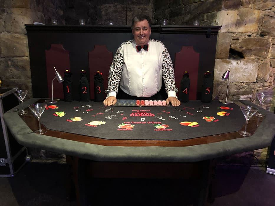 A croupier behind a cocktail casino table at Bond Parties